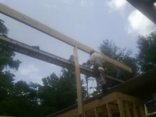 Carpenter setting a ridge beam over a new addition frame — Ice Dam Removal by Roofing Brothers in Friendswood