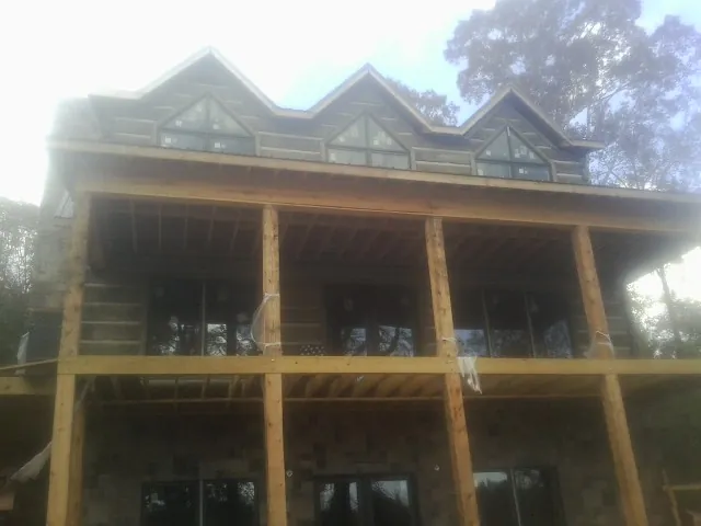 Dormers and porch framing on a large log home under construction — Roof Coating work by our crew in Friendswood