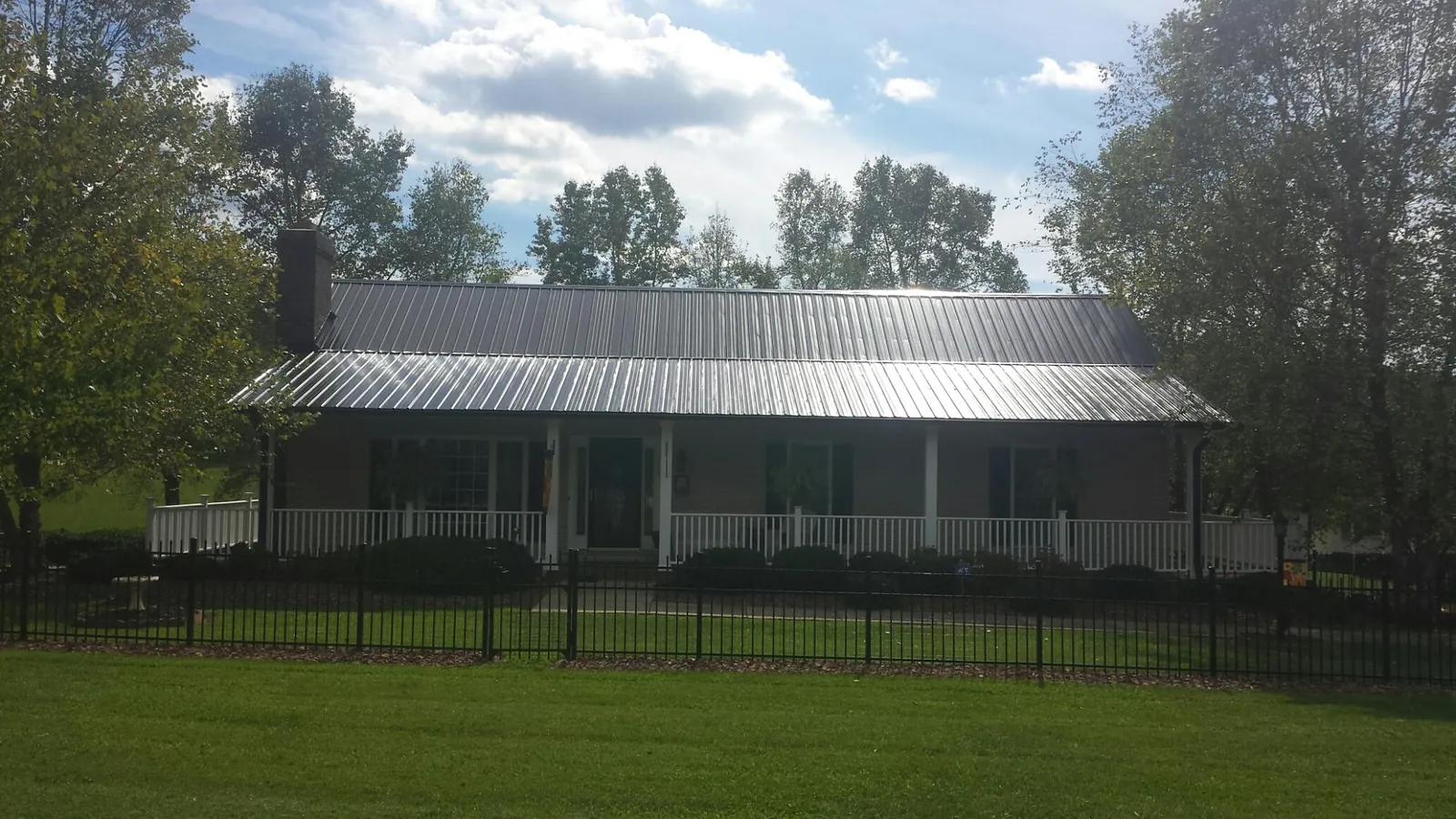 Gray metal roof on a brick ranch with a full width front porch — Gutter Guard Installation work by our crew in Friendswood