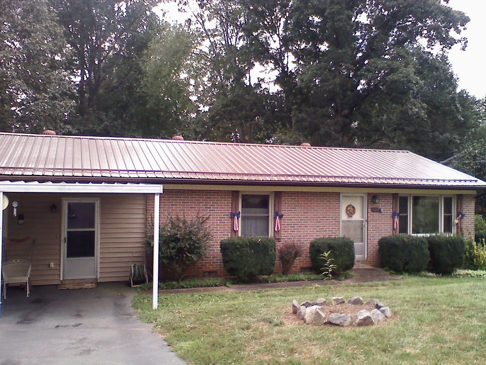 Bronze metal roof and carport on a brick ranch home — Roof Repair work by our crew in Friendswood