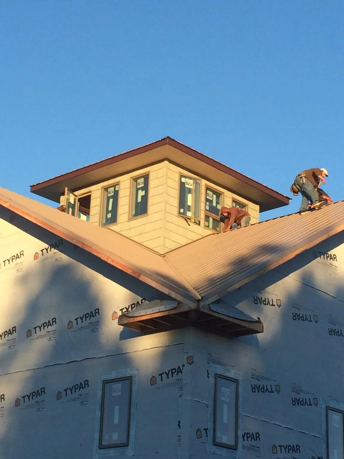 Roofers working around a rooftop cupola on a new metal roof at sunset — Roof Waterproofing in Friendswood by Roofing Brothers